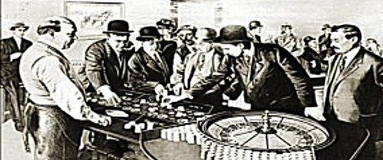 Historisk bild från ett casino där en grupp män spelar roulette. Dealern tittar på när de placerar sina insatser. 